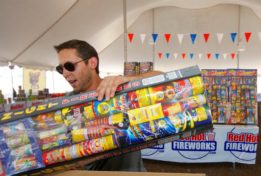 In this photo taken on Wednesday, July 2, 2014, Brian Herrman, a co-owner of Red Hot Fireworks in Phoenix, puts out new items on the shelves as sales of fireworks have been brisk at the store. (The Associated Press/Ross D. Franklin)