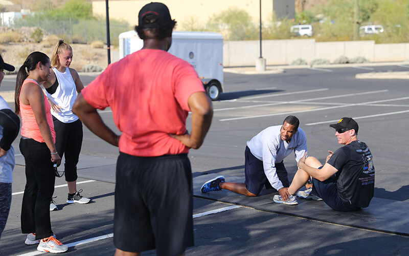 Phoenix Police Officer Christopher McCloud, second from right, recruiter for the department, talks about proper sit-up form to a 2017 class of police recruits. (Cronkite News/Chris Benincaso)