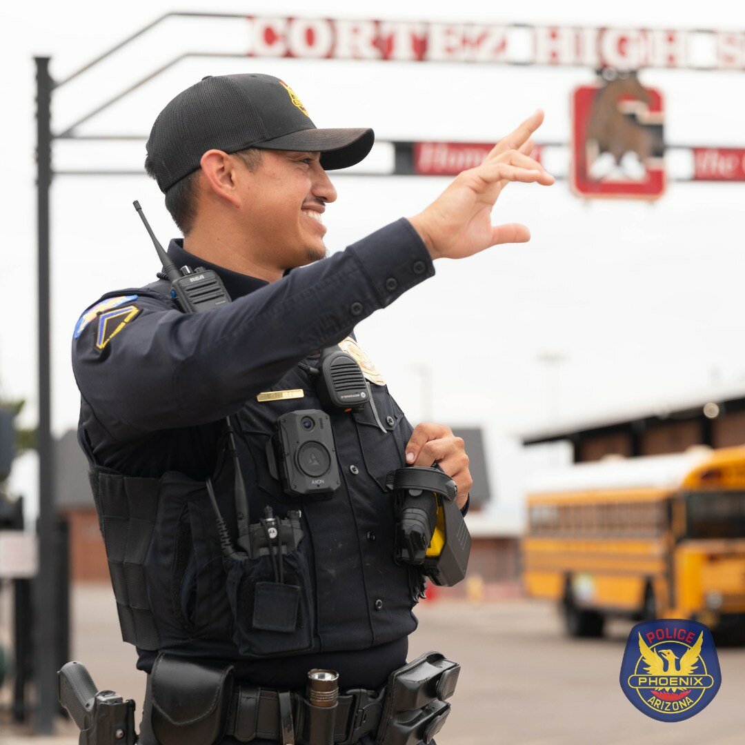 Officer Marcus Telez, a Phoenix police school resource officer at Cortez High School, waves to students on campus. A state task force looking for ways to curb violence at schools is looking at ways beyond funding more SROs to meet those goals. (Courtesy Phoenix Police Department)