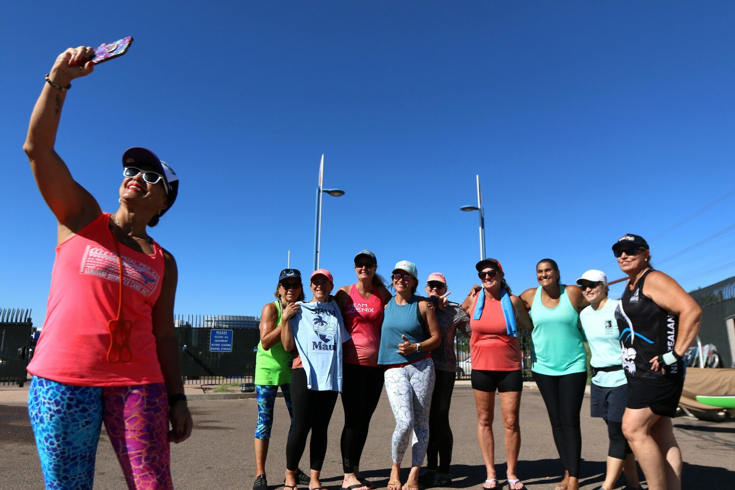 Betty Flores, a member of Na Leo ’O Ke Kai, takes a selfie with Na Leo and TAZ members at Tempe Town Lake on Sept. 30, 2023. “All the different clubs, even though we race against each other, we’re all still one big family,” said Ryan Udarbe, president of Na Leo ’O Ke Kai outrigger canoe club. (Photo by Kevinjonah Paguio/Cronkite News)