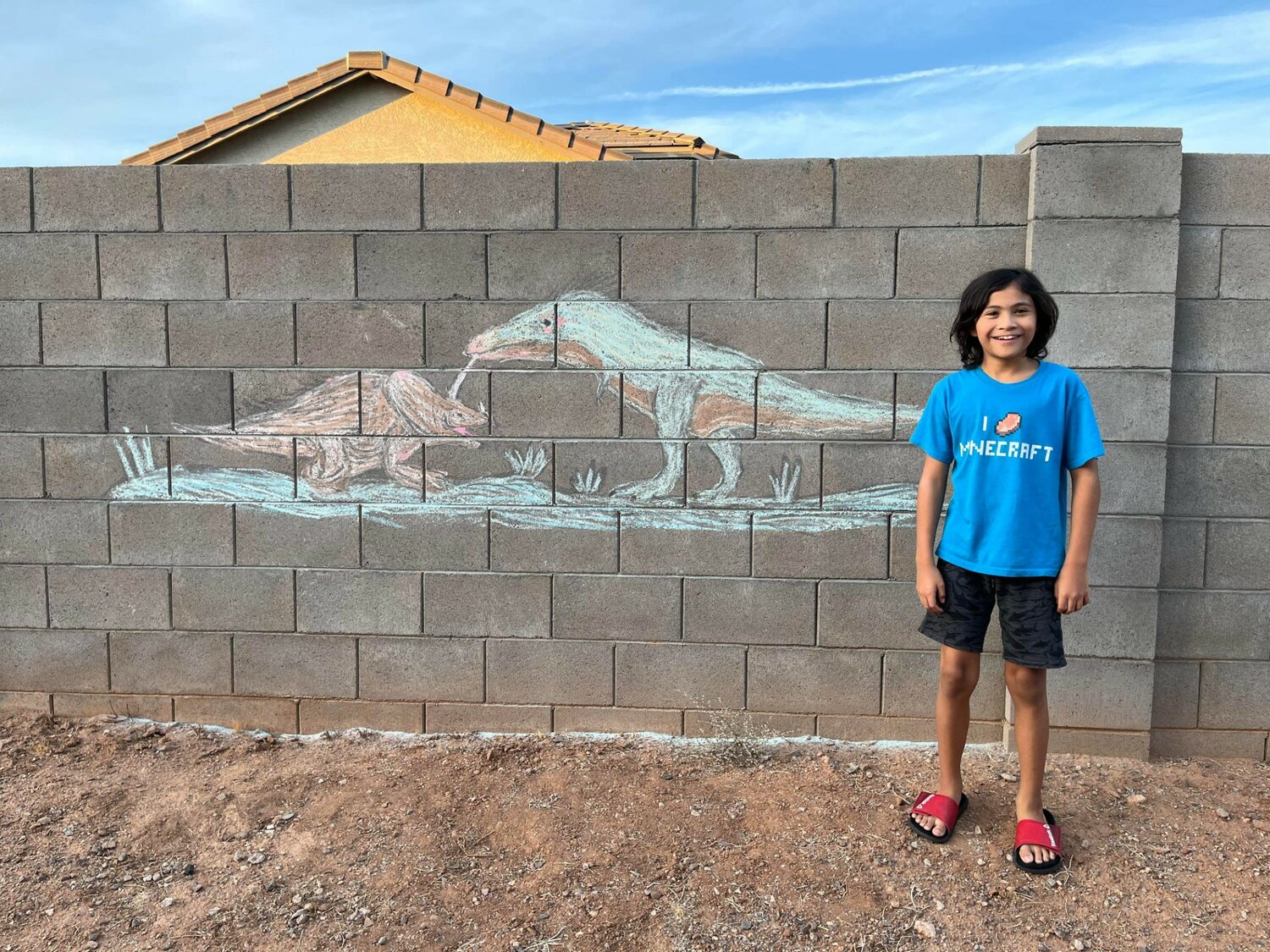 Rocky Valdivia stands next to the dinosaurs he drew to win the 12-and-under age group at the Halloween Chalk Contest.