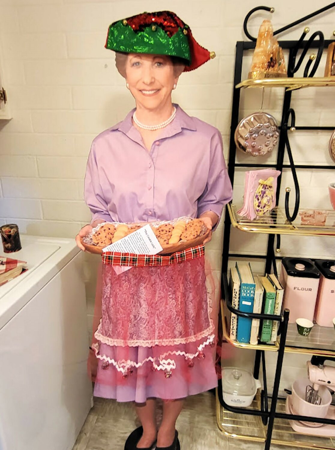 The Cookie Lady as she stands today in the kitchen of the Del Webb Sun Cities Museum. Former Board Trustee Jo Ruck served as the model for the cardboard cutout. Shown here is the Cookie Lady at last year’s holiday open house.