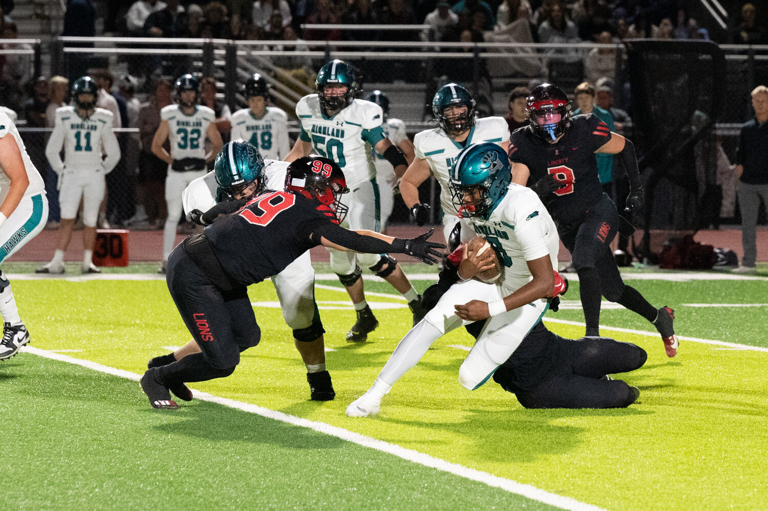 Liberty nose guard Ben Bryant (99) reaches for Highland wideout Crew Crandall (8) during the Lions' Open Semifinal victory on Saturday at Mountain Ridge High School. (Courtesy Picture Lady Photography for West Valley Preps)