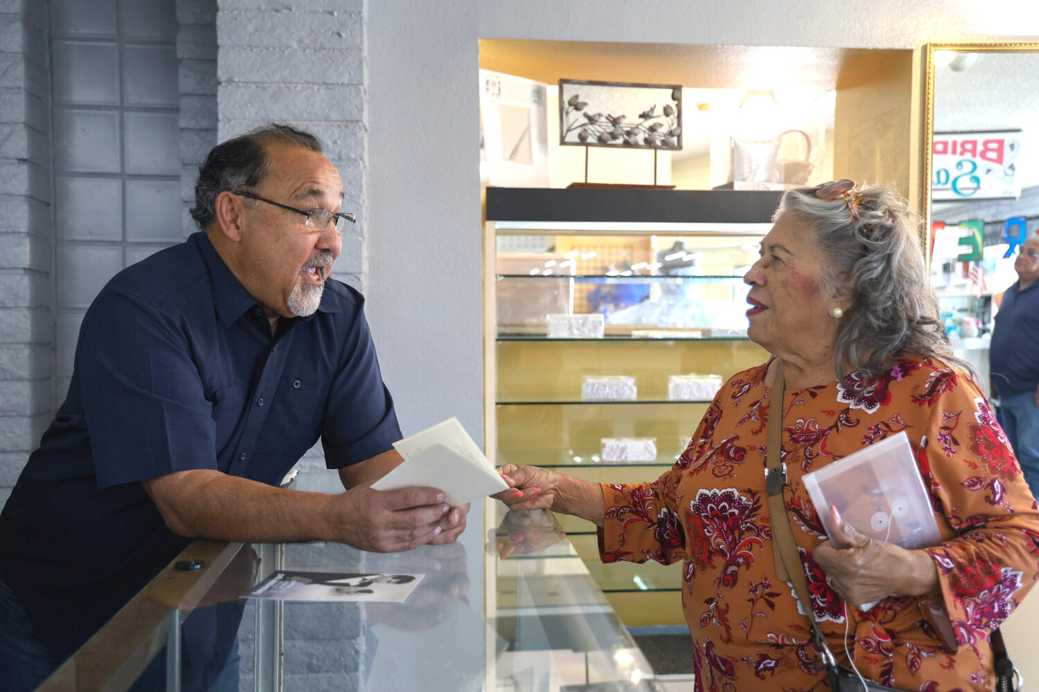 Raoul Torrez, left, and Bertha Gonzalez discuss the wedding dress she bought from Azteca Bridal in 1967. Photo taken on Nov. 21, 2023. (Photo by Sam Volante/Cronkite News)
